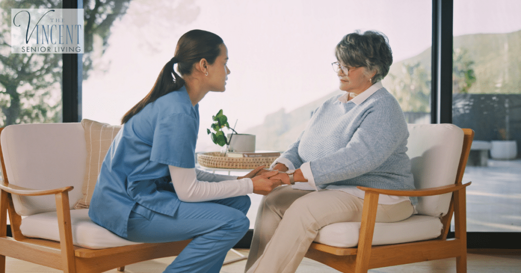 Compassionate nurse talking with a senior woman and holding her hands during the transition to memory care.